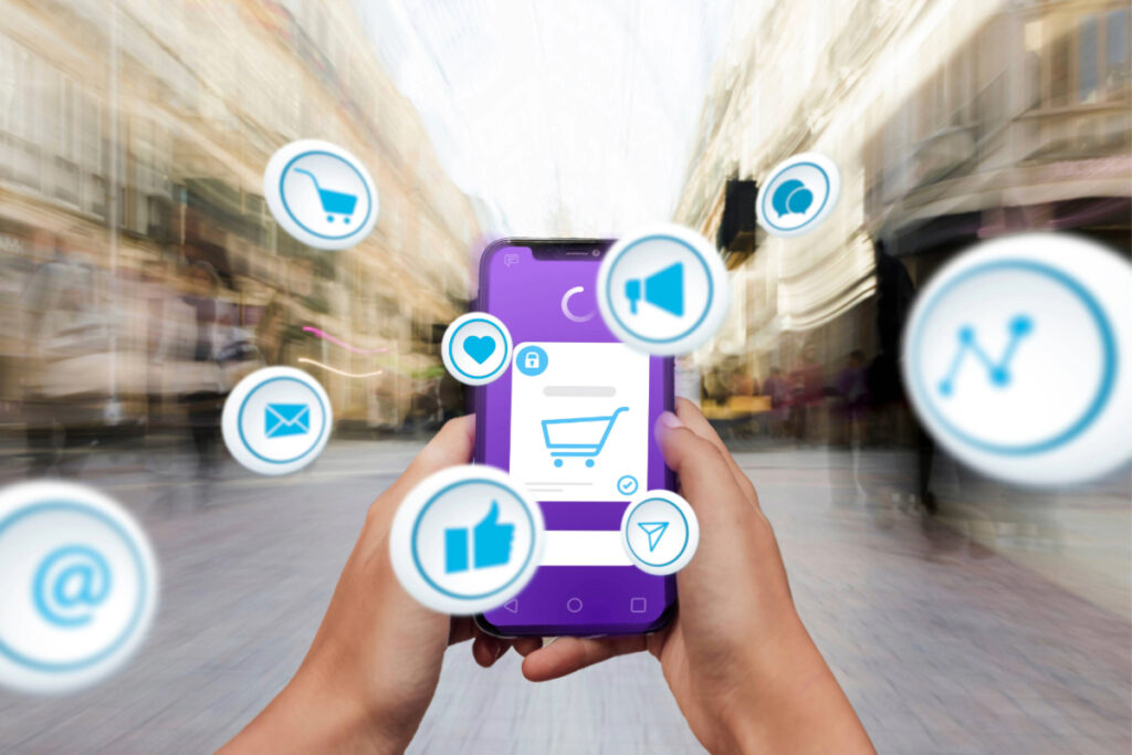 duas maos segurando um celular com diversos icones referente a compra online